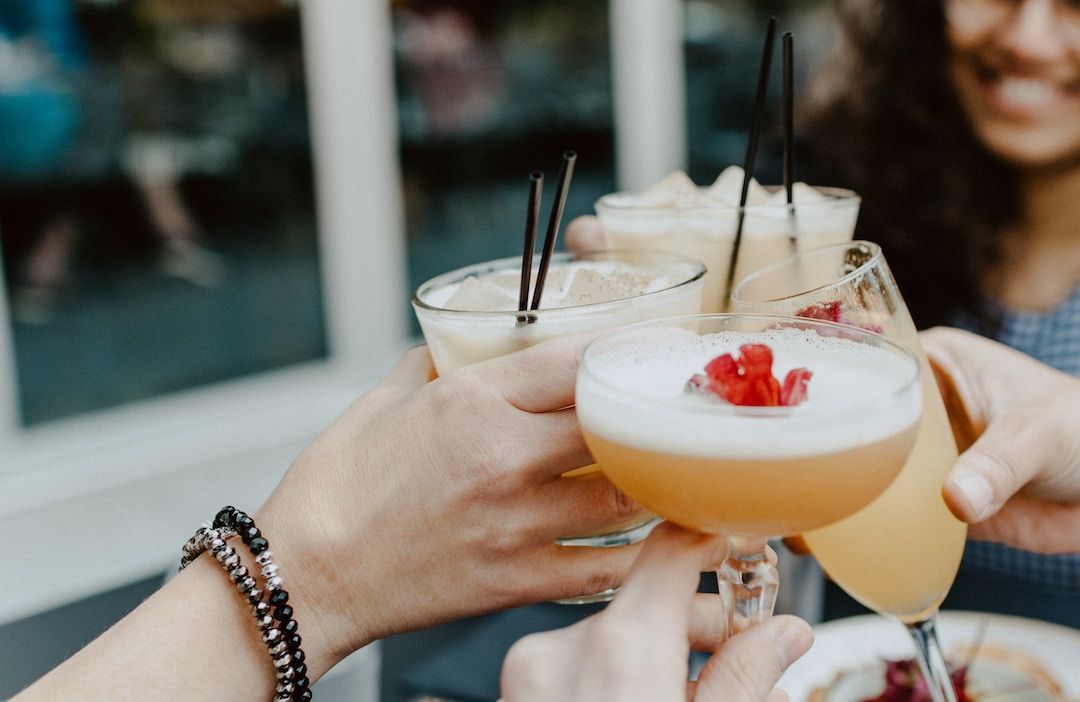 Friends raising colorful drinks together in a celebratory toast