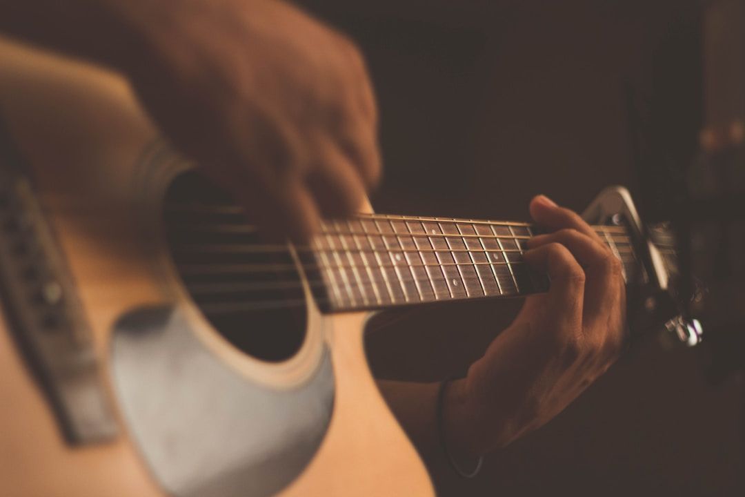 Close-up of hands playing an acoustic guitar in warm light
