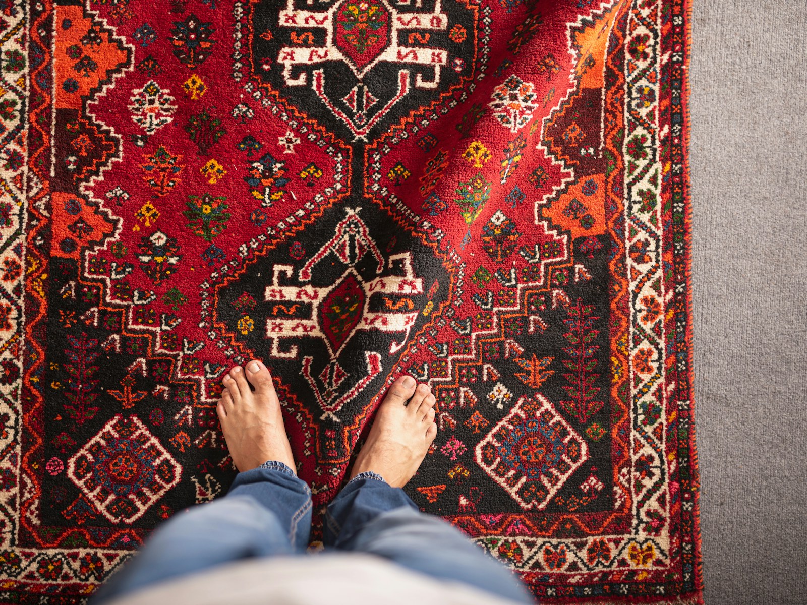 Bare feet resting on a red patterned rug at home