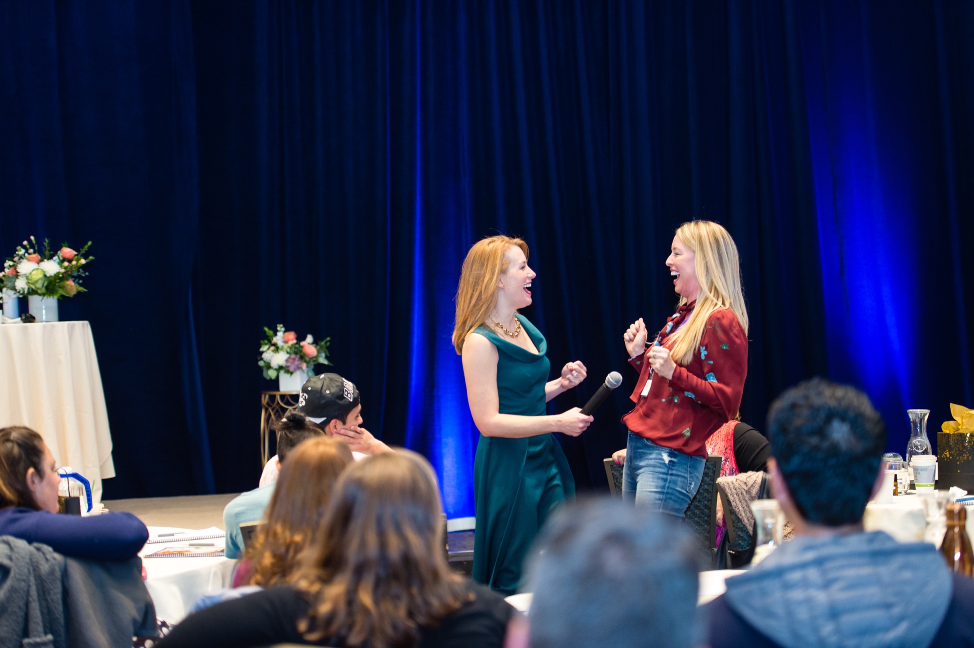 Tamara Rose coaching a woman live on stage in front of the room