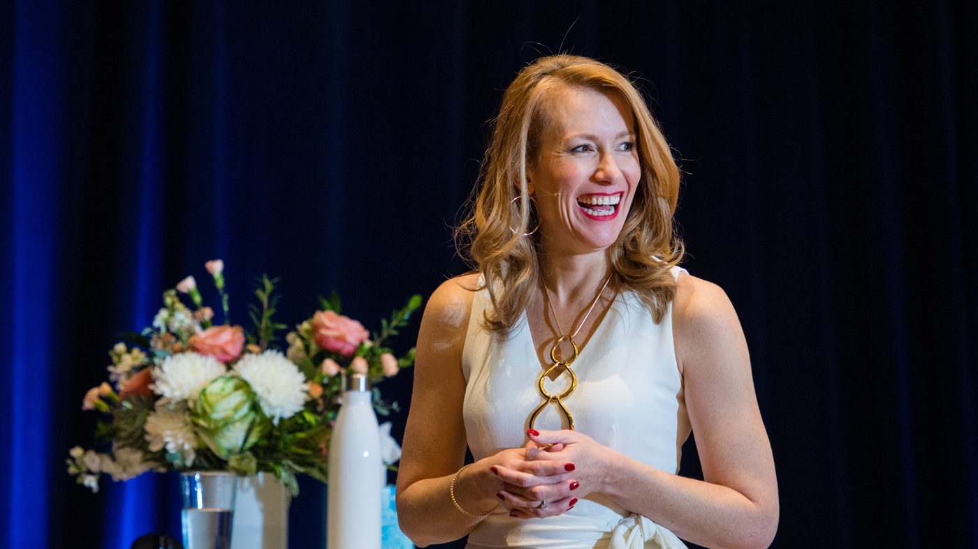 Tamara Rose laughing on stage in a white jumpsuit