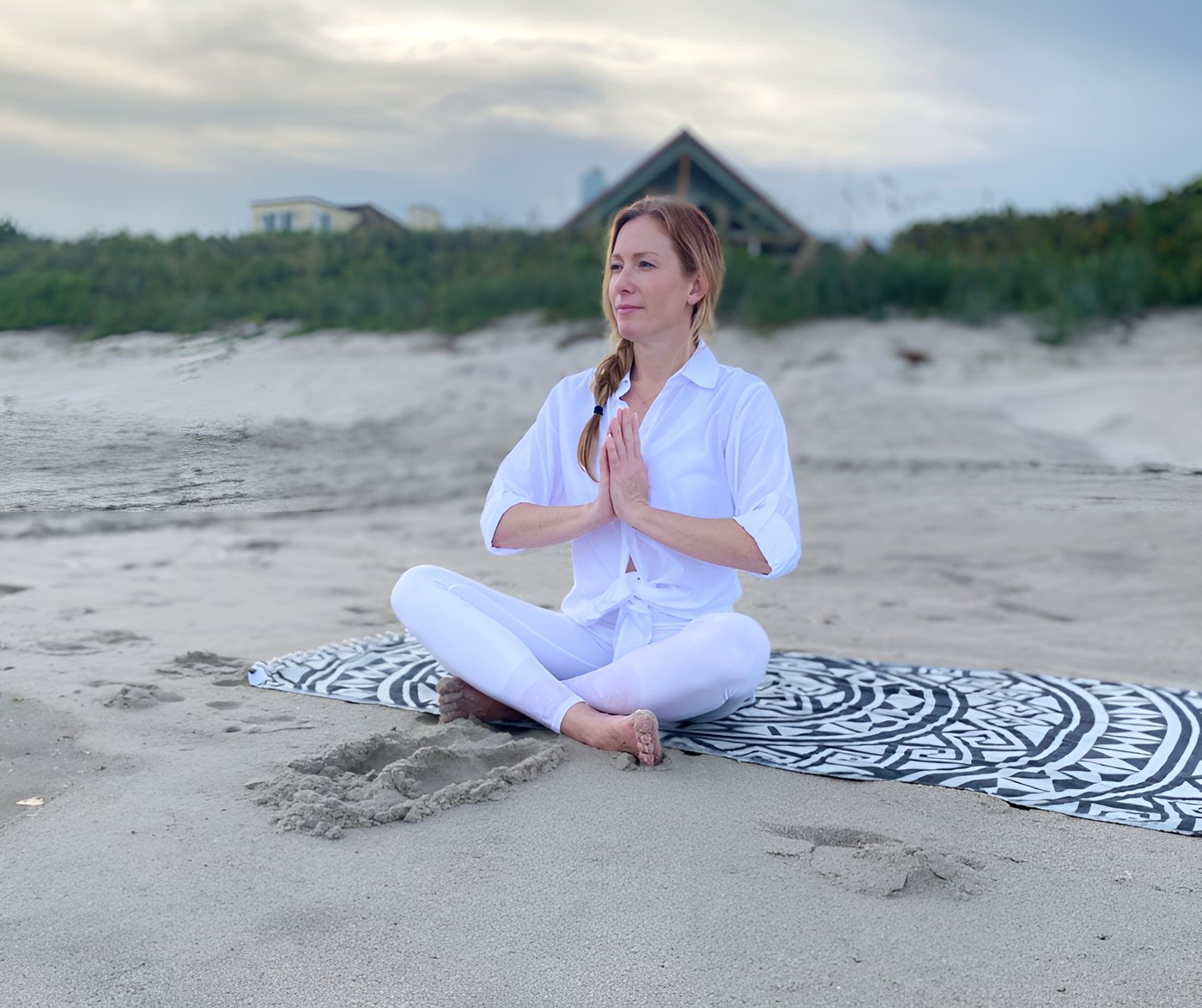 Tamara Rose meditating on the beach with her hands at her heart