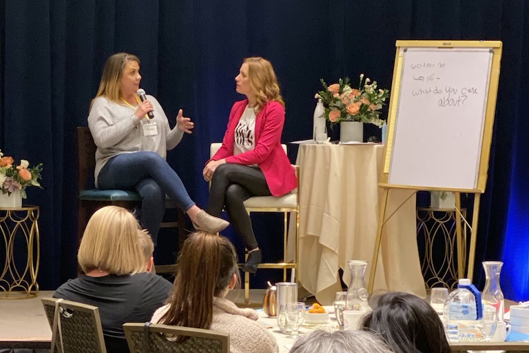 Tamara Rose in conversation with a business owner on stage beside a whiteboard