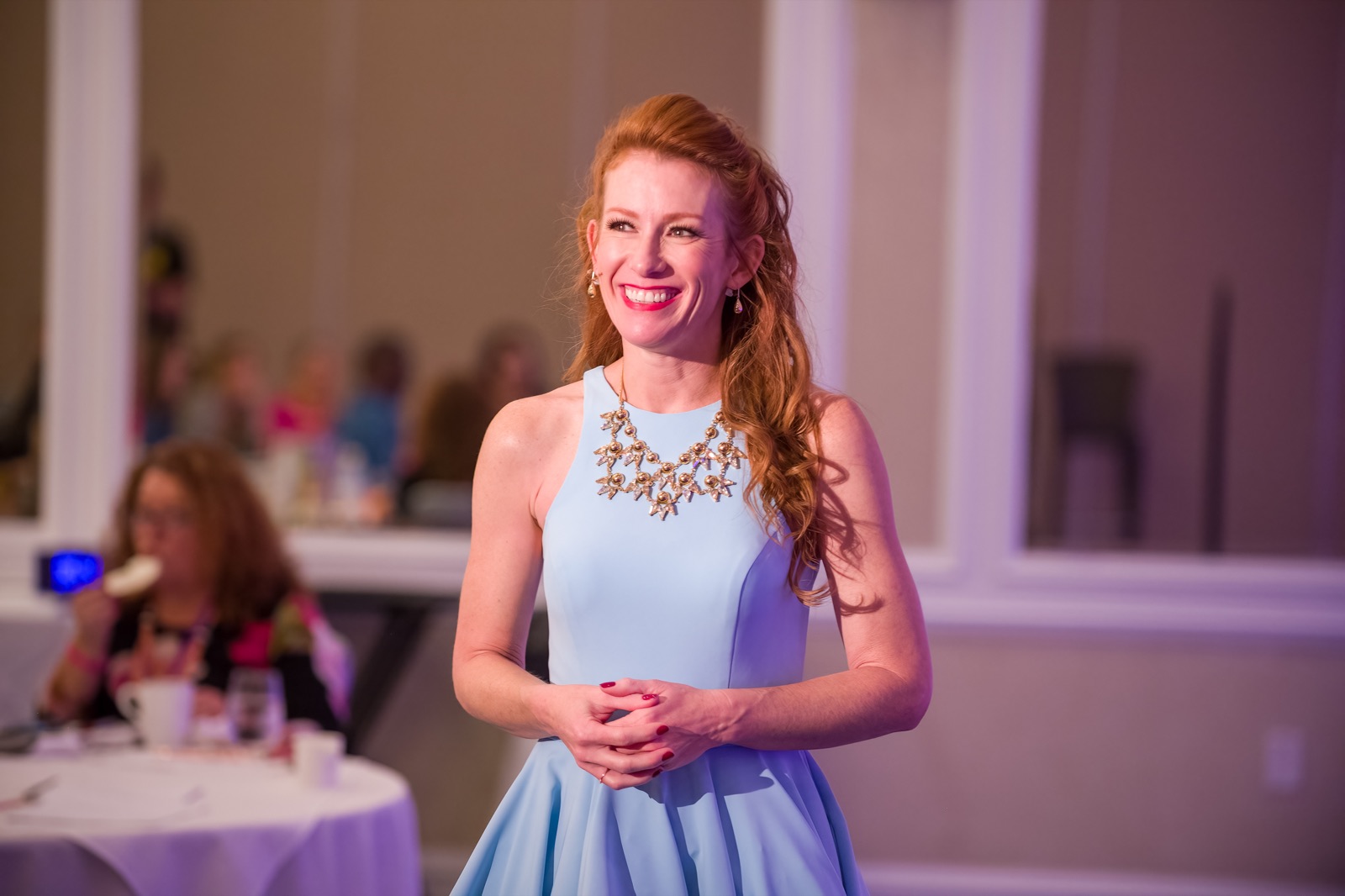 Tamara Rose smiling as she speaks to a room of women at a luncheon