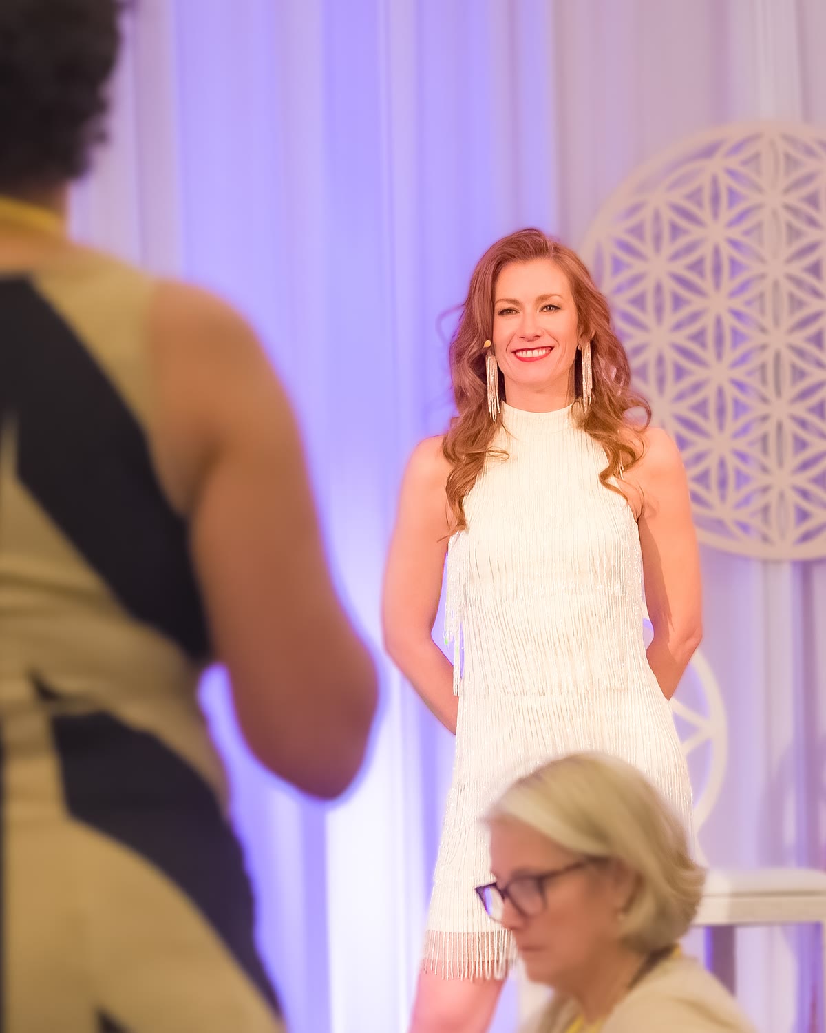 Tamara Rose smiling on stage at a women's event as the audience listens